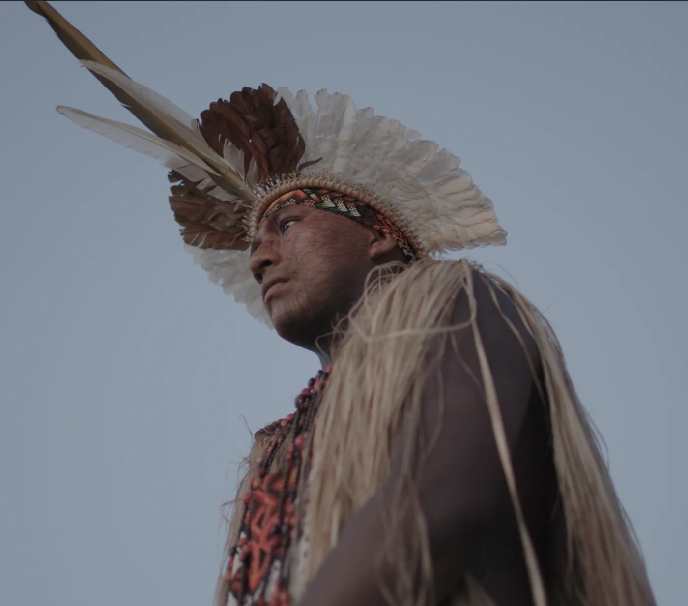 Portrait en contre-plongée d’un homme portant une grande coiffe de plumes.